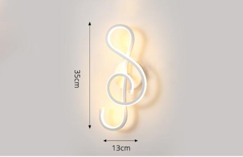 The Note Curved LED Wall Sconce in matte white beside a bed